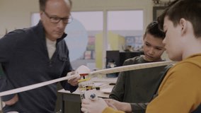 Teacher helping junior high boy students assemble wind turbine in classroom - Powered by Shutterstock - Get 15% off with code: PIKWIZARD15