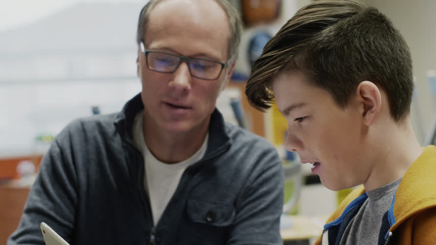 Male junior high teacher with digital tablet helping boy student with math homework - Powered by Shutterstock - Get 15% off with code: PIKWIZARD15
