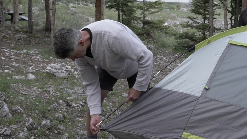Man pitching tent at campsite in woods