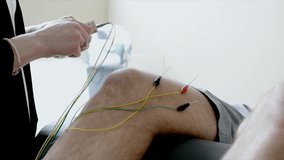 Female acupuncturist using electric needles on knee of man on clinic examination table - Powered by Shutterstock - Get 15% off with code: PIKWIZARD15