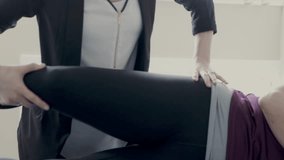 Female physiotherapist stretching hip of client in clinic examination room - Powered by Shutterstock - Get 15% off with code: PIKWIZARD15