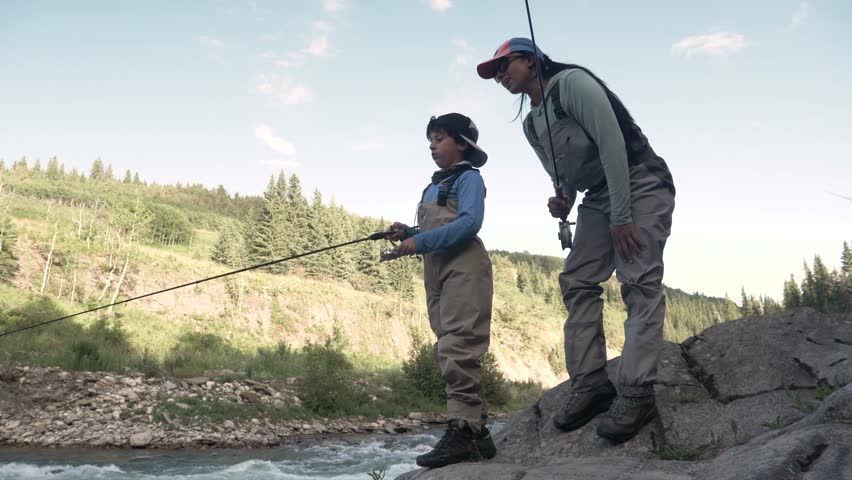 Slow motion of mother teaching son to fish in river