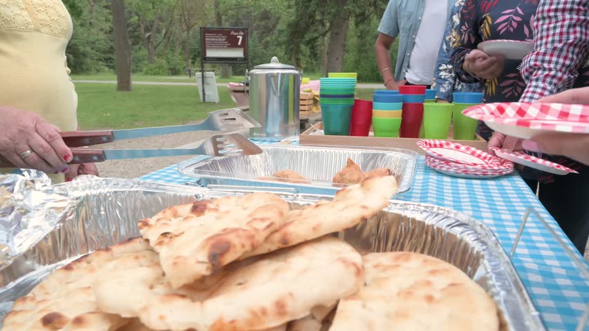 Indian woman and grandson serving food at picnic in park