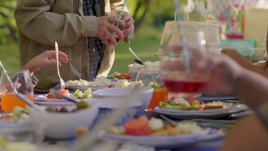 Multigenerational family eating and drinking at picnic table