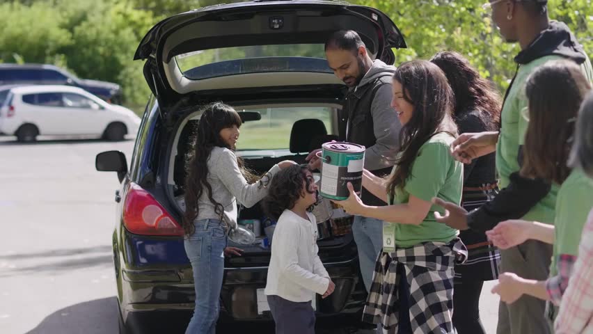 Smiling volunteers unloading paint cans for recycling from car
