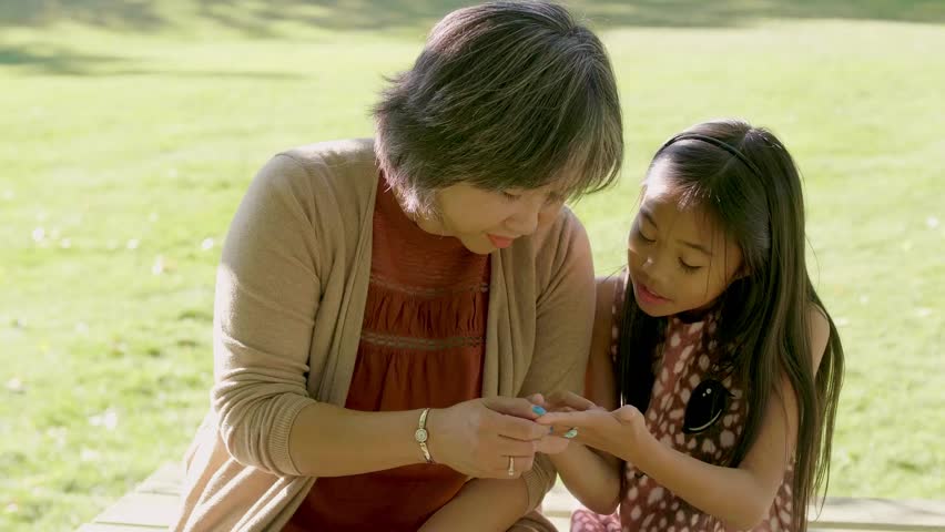 Mother and daughter looking at hand in park