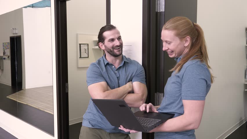 Physiotherapists with laptop in rehabilitation clinic corridor