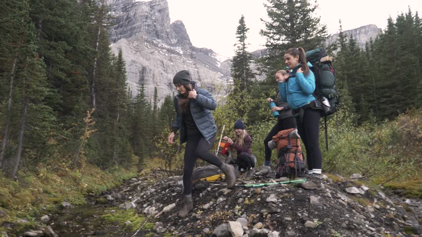 Young women friends taking a break from hing at mountain stream
