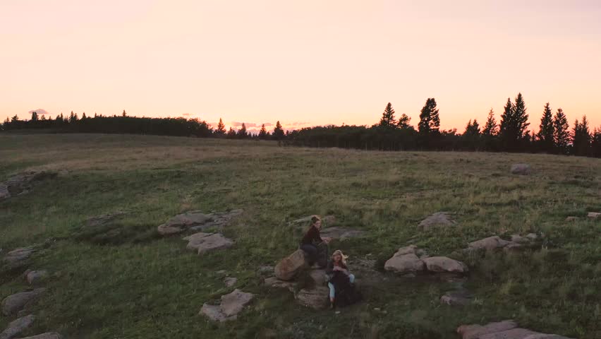 Two friends with backpacks resting on rocks