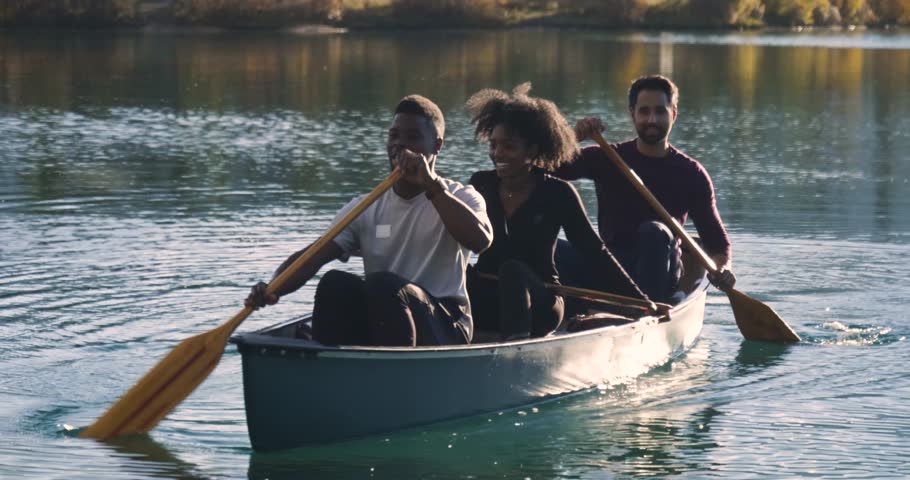 Happy friends canoeing on sunny lake