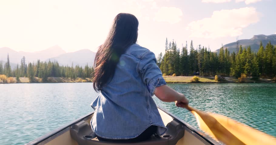 Portrait happy woman canoeing on sunny mountain lake