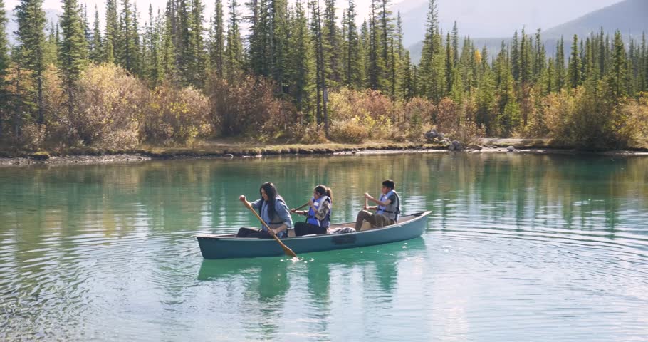 Family in life jackets canoeing on sunny lake