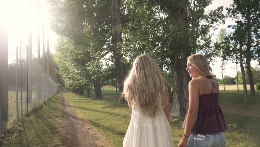 Teenage girl friends walking in sunny summer park