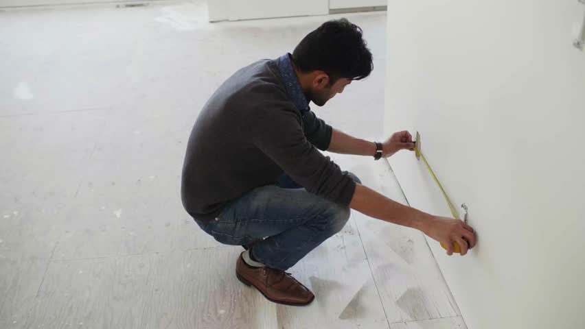 Male homebuilder measuring electrical outlet at home construction site