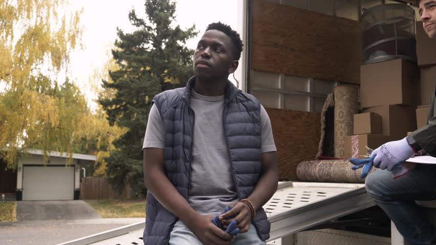 Thoughtful male mover taking a break outside moving van