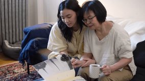 Mother and daughter looking at photo album in living room - Powered by Shutterstock - Get 15% off with code: PIKWIZARD15