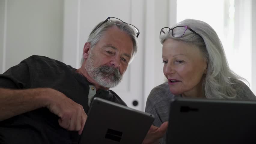 Laughing senior couple talking using digital tablet and laptop - Powered by Shutterstock - Get 15% off with code: PIKWIZARD15