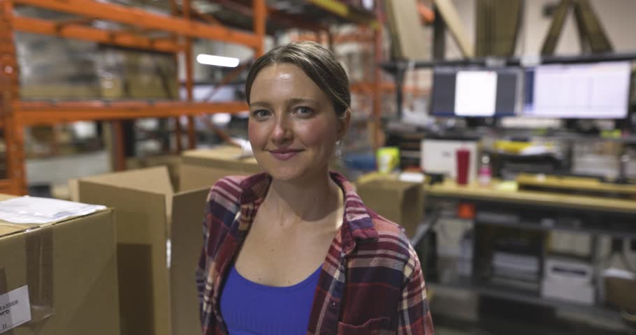 Portrait confident female worker with shipping boxes in warehouse