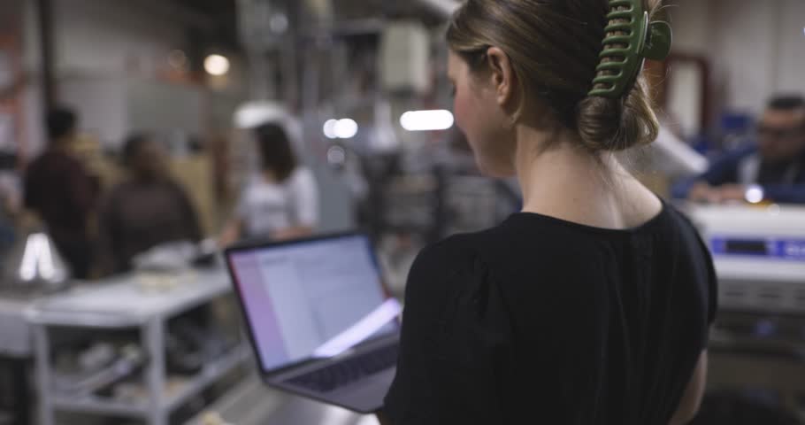 Portrait confident female supervisor with laptop working in factory