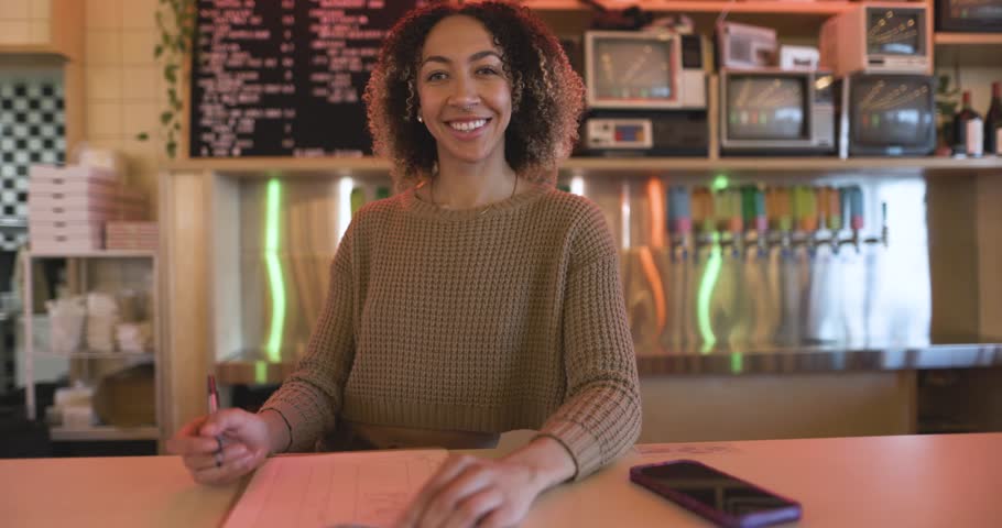 Portrait smiling female brewery owner working behind bar counter
