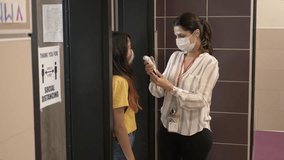 Slow motion of teacher wearing mask taking students temperature - Powered by Shutterstock - Get 15% off with code: PIKWIZARD15