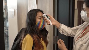 Slow motion of teacher wearing mask taking students temperature - Powered by Shutterstock - Get 15% off with code: PIKWIZARD15