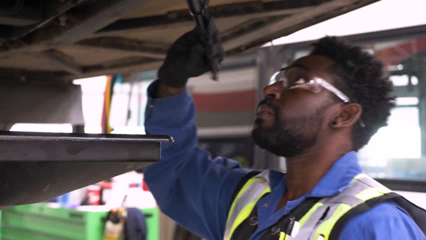 Male mechanic with flashlight inspecting undercarriage of bus
