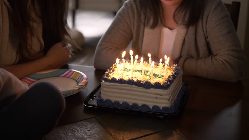 Slow motion of birthday cake with candles lit up on table