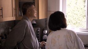 Senior couple in bathrobe looking out kitchen window - Powered by Shutterstock - Get 15% off with code: PIKWIZARD15