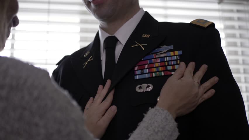 Wife touching ribbon bar on jacket of military officer husband