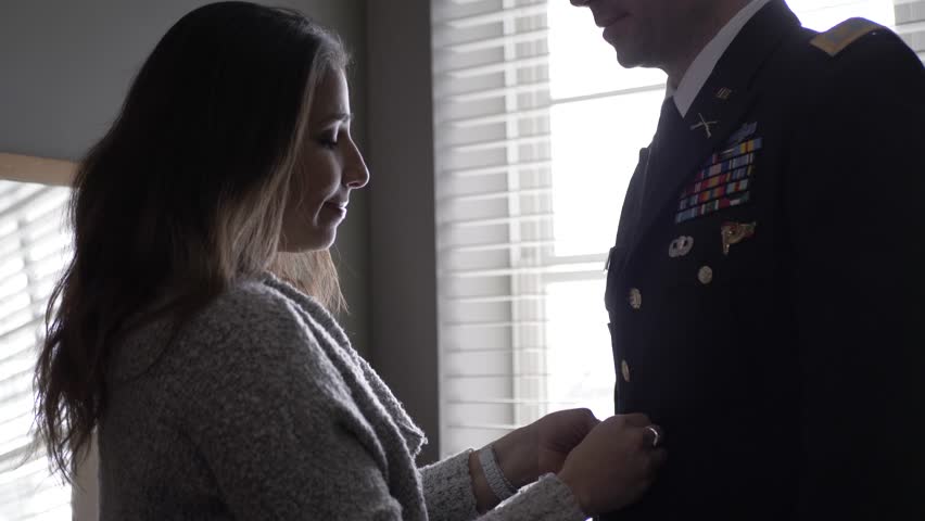 Wife buttoning jacket of formal uniform for officer husband