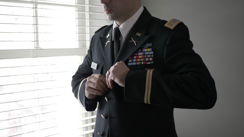 Male military officer putting on formal dress uniform jacket