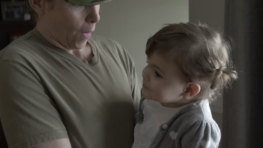 Soldier mother holding preschool daughter sucking thumb