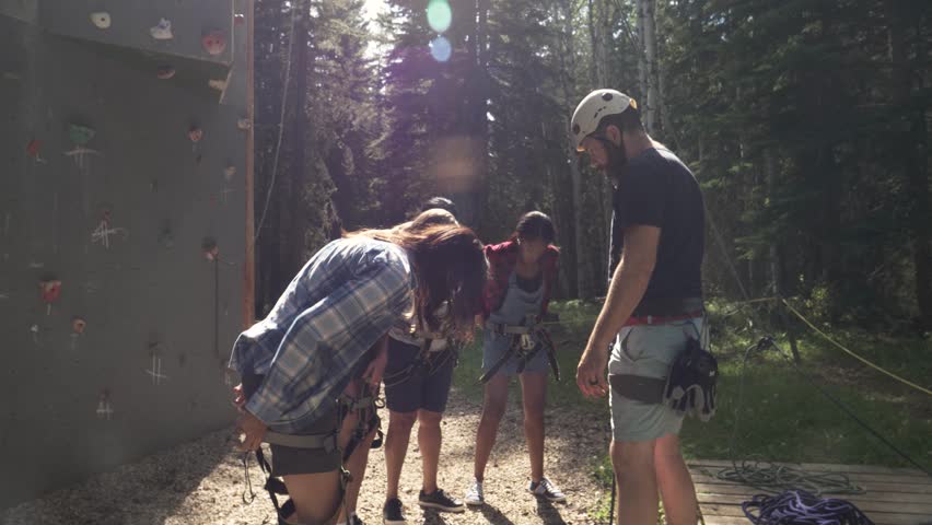 Slow motion of climbing instructor teaching women to attach rope