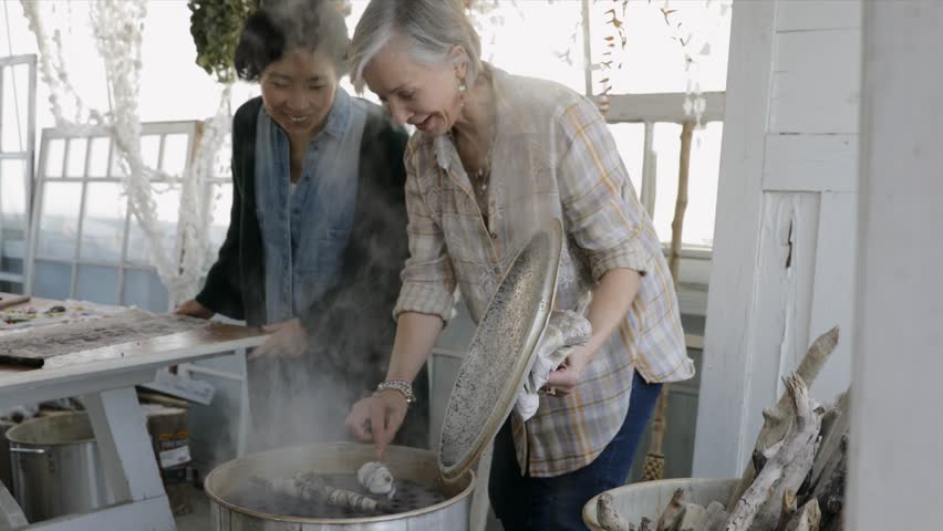 Women steaming dried flower bundles for paper making