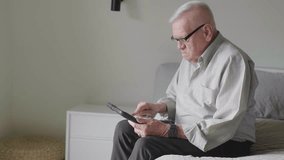 Senior man using digital tablet on bed at home - Powered by Shutterstock - Get 15% off with code: PIKWIZARD15