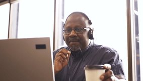 Businessman with headphones video conferencing at laptop in office - Powered by Shutterstock - Get 15% off with code: PIKWIZARD15
