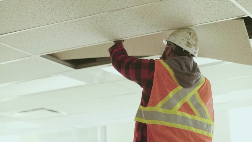 Construction worker removing ceiling tile