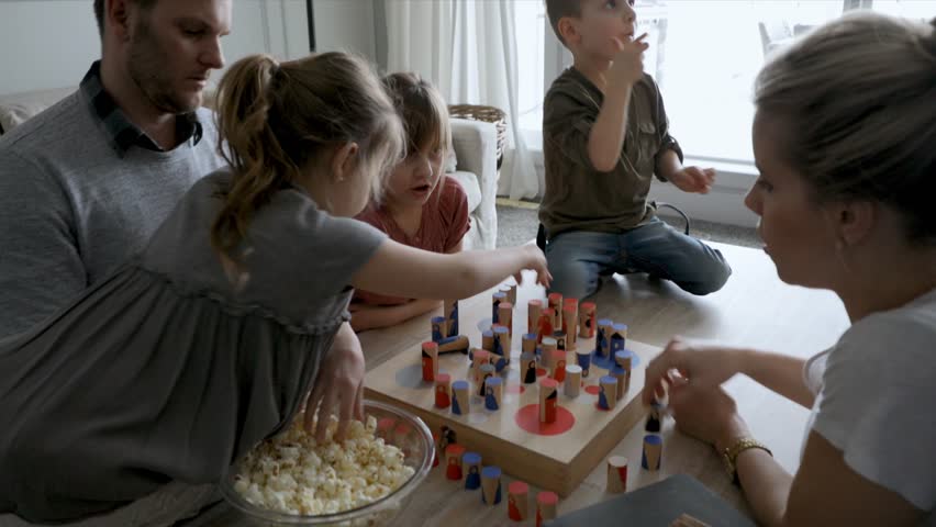 Family eating popcorn and playing game at living room coffee table