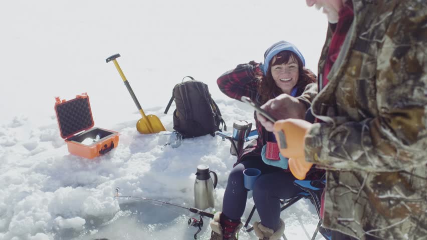 Senior couple using phone on frozen alpine lake