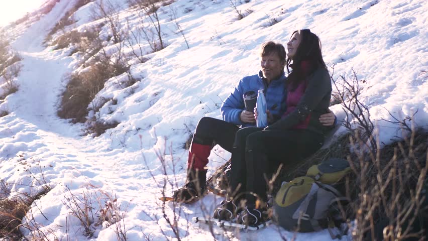 Slow motion of couple stopping for a drink on winter he in snow