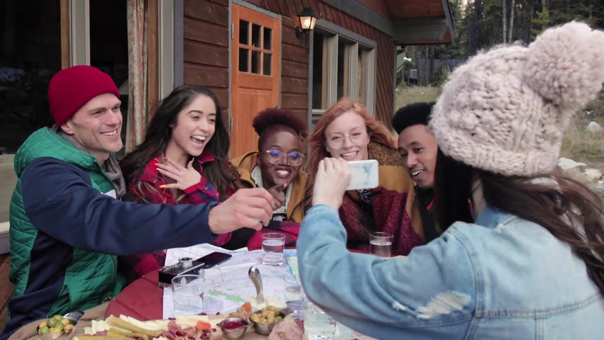 Happy young friends taking selfie with camera phone on cabin balcony