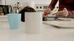 Son helping mother make peanut butter and jelly sandwich in kitchen - Powered by Shutterstock - Get 15% off with code: PIKWIZARD15