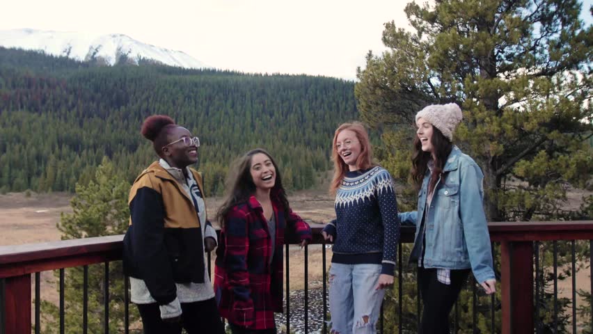 Happy young women friends laughing on cabin balcony