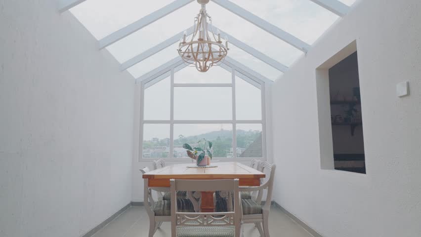 Bright and airy dining room with a glass roof, large windows, and a classic wooden dining table set.