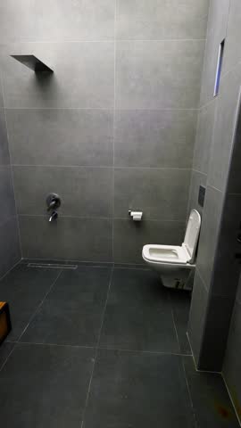 Toilet bowl and washbasin inside made of marble. Walls are lined with ceramic tiles. White Toilet Interior Template with Toilet and Chest of Drawers Vertical video