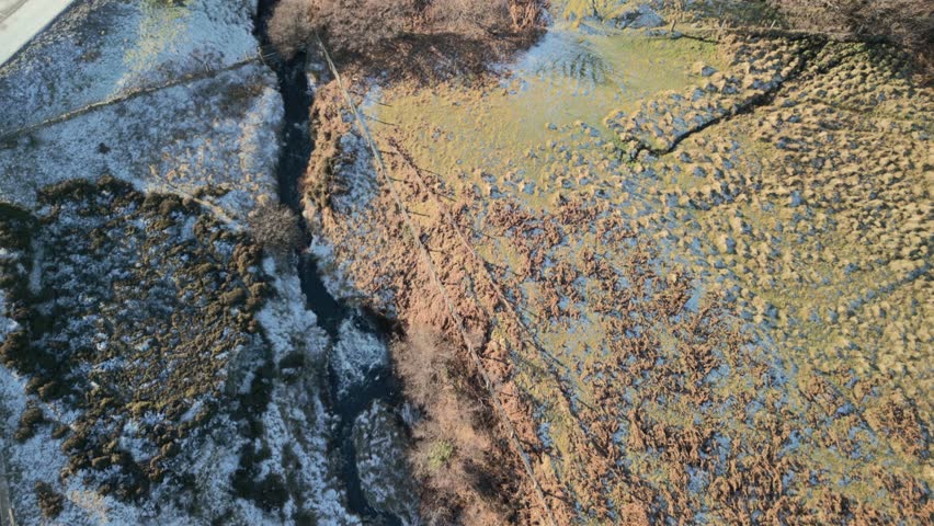 Flyover reveal of waterfall cascading down to frost covered black rocky beach, early morning in winter at Kilt Rock Waterfall, Isle of Skye, Western Highlands, Scotland, UK