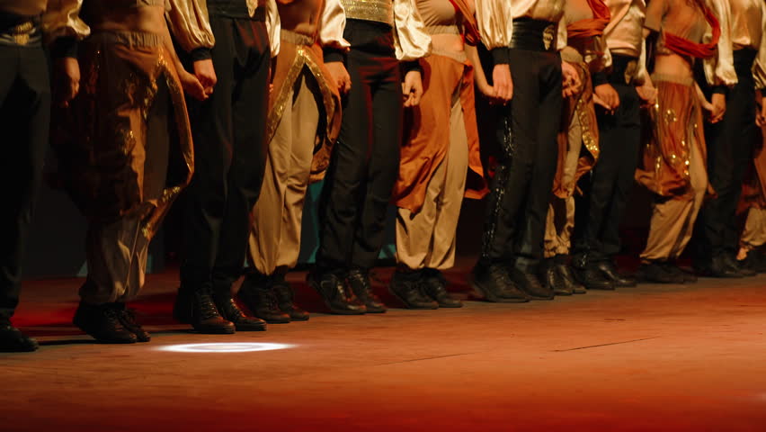 Actors on stage join hands and form a circle, dancing. Slow motion. Turkish night.