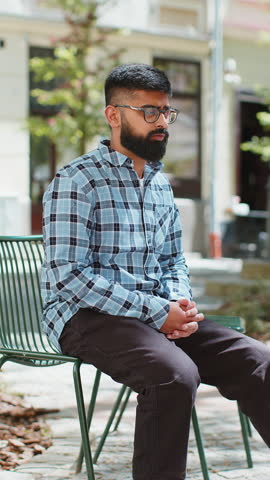 Indian man feeling sudden strong abdominal stomach liver kidney ache gastritis problem outdoors. Hispanic guy having symptom poisoning diarrhea indigestion peptic ulcer pancreatitis on city street