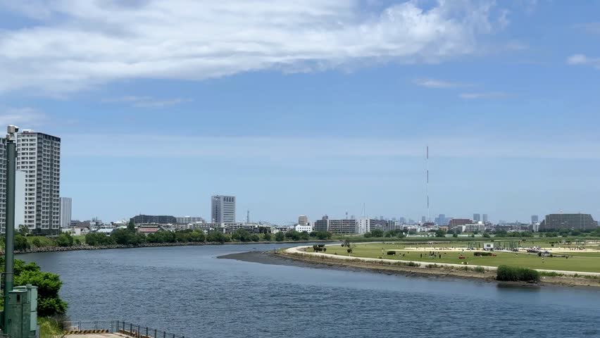 Skyline view of a city across a river with a grassy area in the foreground on a sunny day